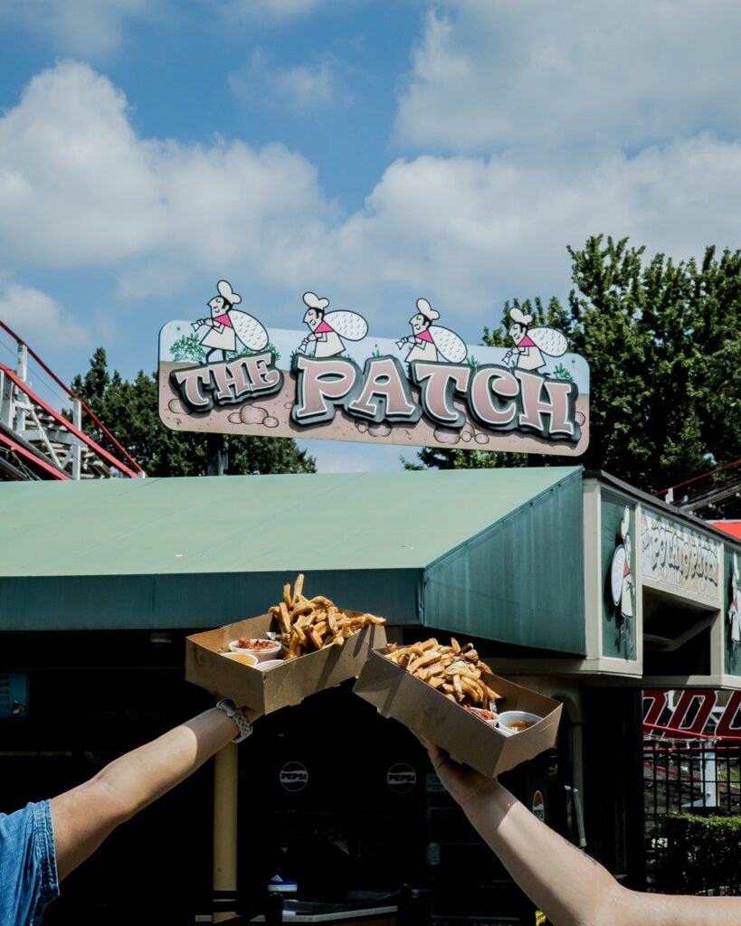 Two people hold up boxes of fries.