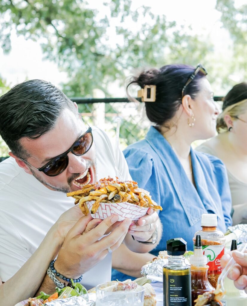 A man moves to bite fried off the top of a dish.