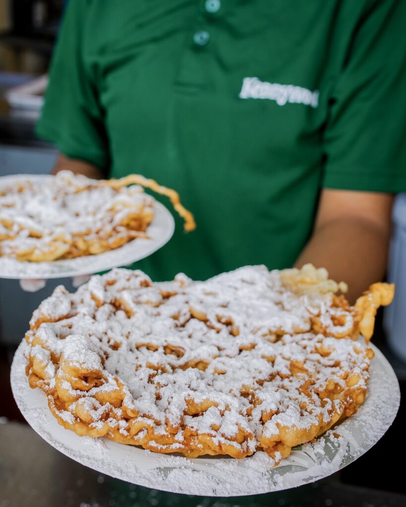 A person holds two funnel cakes.