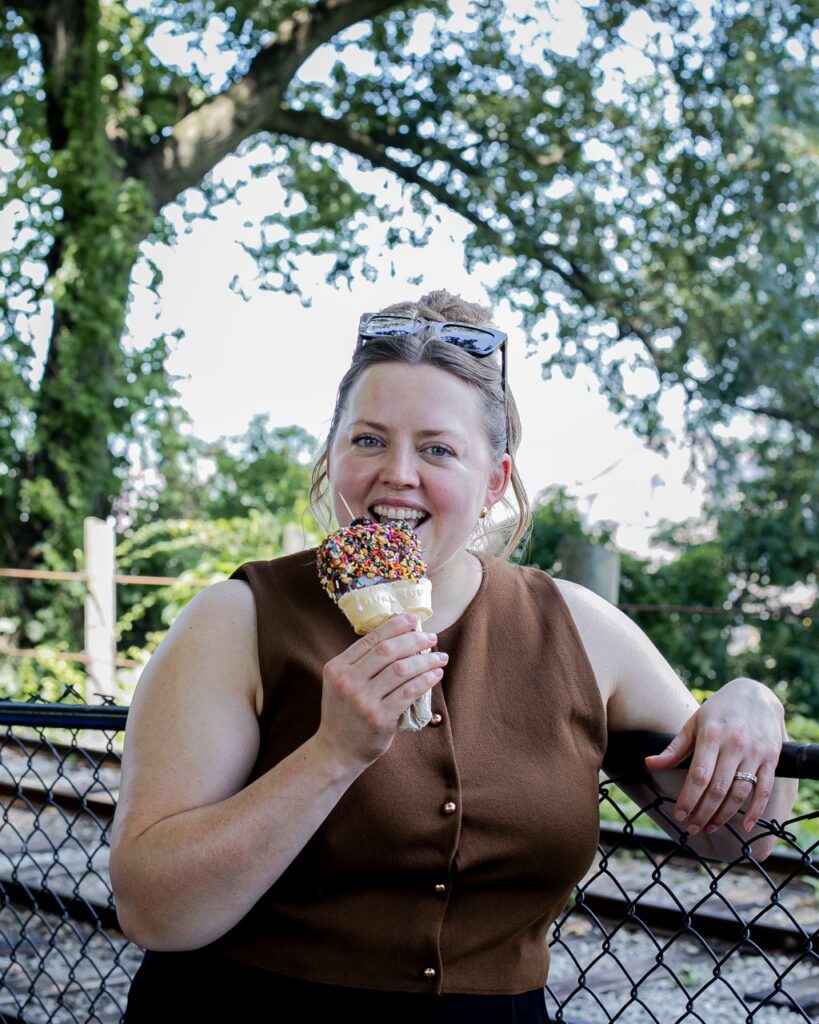 A woman bites into an ice cream cone covered in sprinkles.