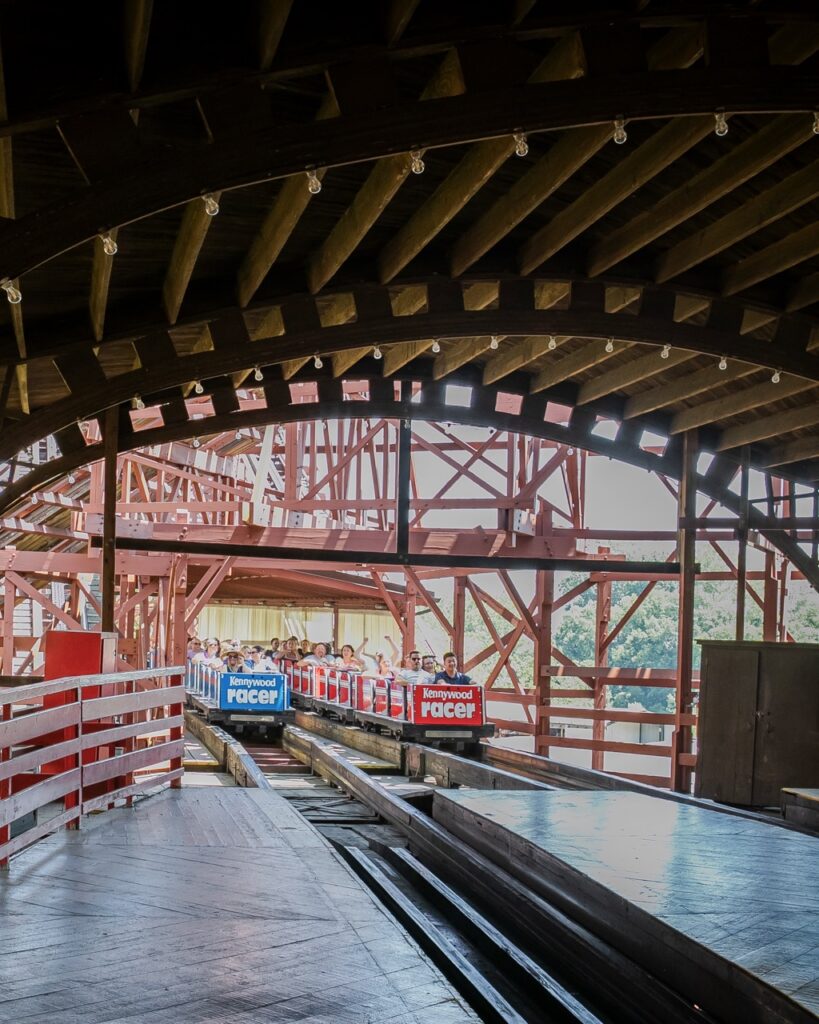 Two roller coasters coming into the station.