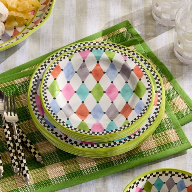 A stack of green and pattern plates on a green plaid cloth.