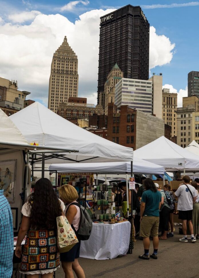 Craft market tents in front of tall buildings in Downtown Pittsburgh.