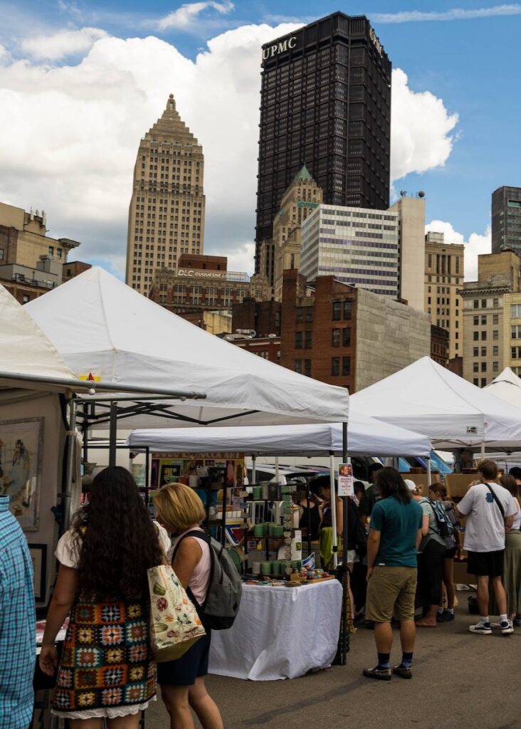 Craft market tents in front of tall buildings in Downtown Pittsburgh.
