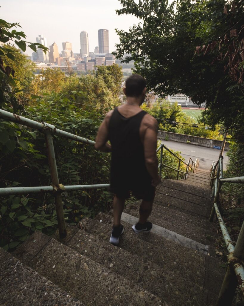 A person walks down city steps with a view of the skyline in the background.
