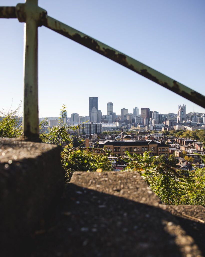 A stair and rail with the view of the city in the background.
