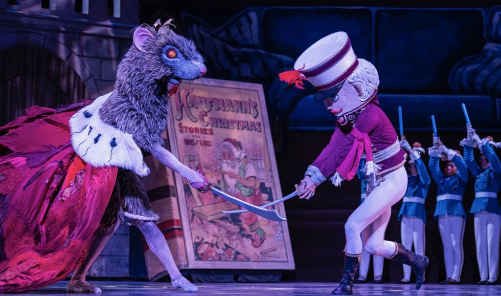 The nutcracker and rat king sword fight on stage.
