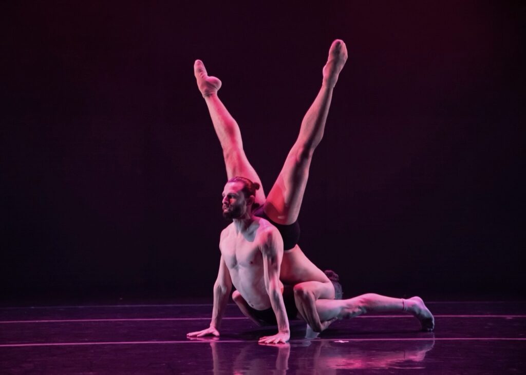 A person fans their legs out above a man's head in a v-shape.