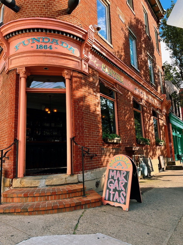 The outside of Esquina Cantina pittsburgh restaurant on the corner in an orange shade.