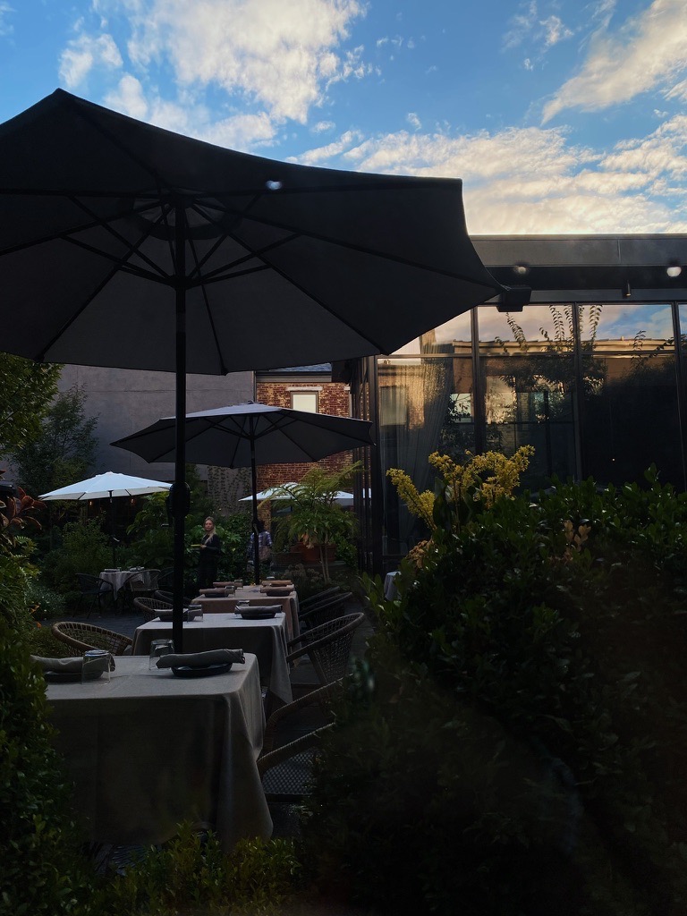 An outdoor patio at sunset with umbrellas and plates beneath.