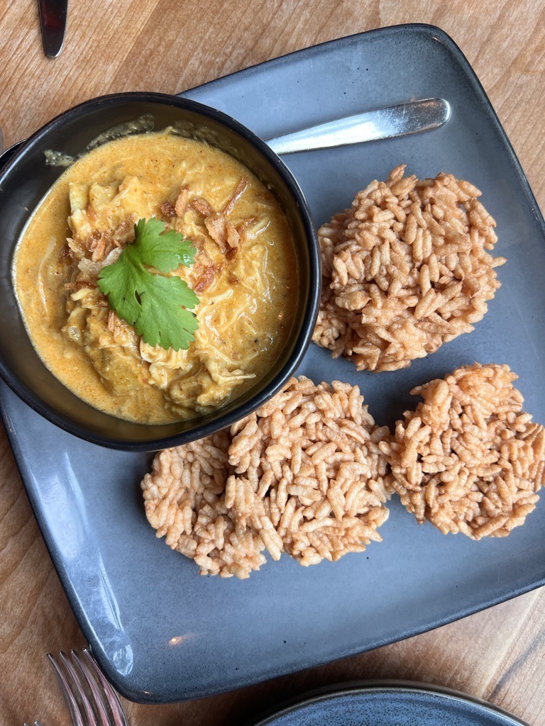 A blue plate with rice pilaf and a bowl of curry.