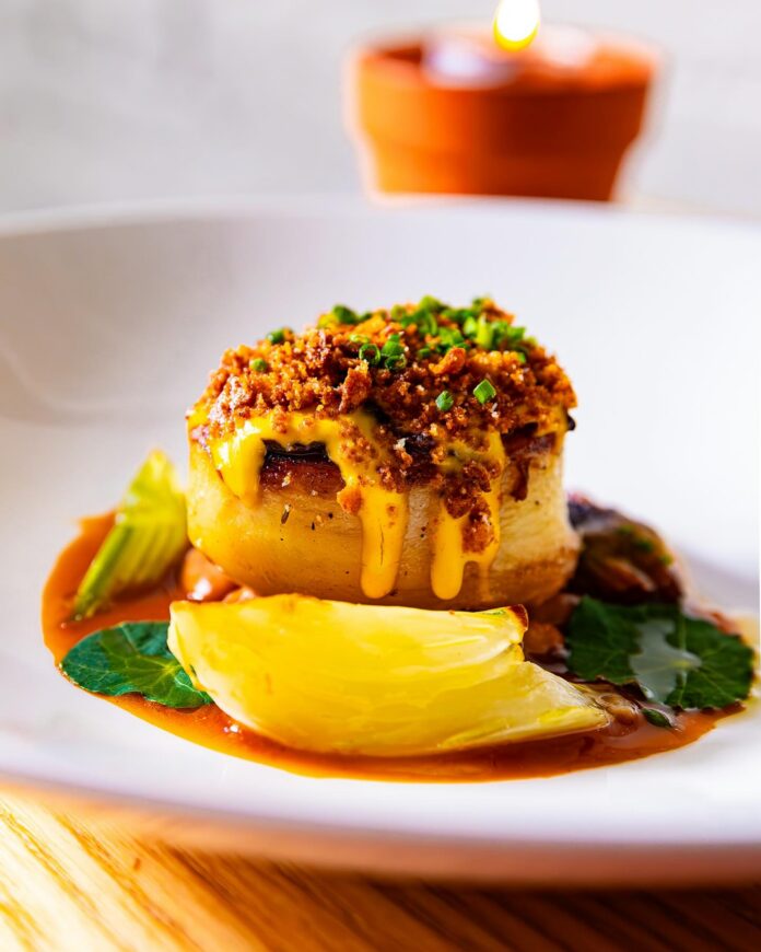 A vegan restaurant week dish featuring a potato stack with vegan melted cheese and other garnishes.