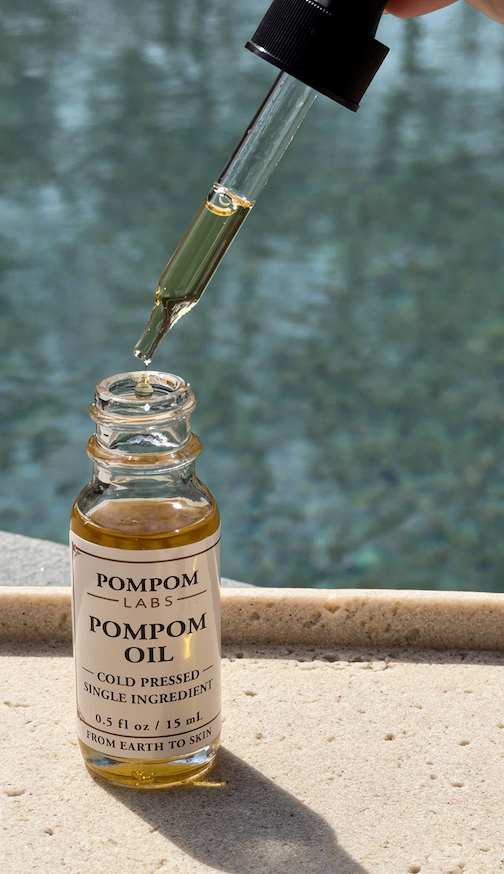 A jar of Pom Pom Oil with the dropper held above the opening.