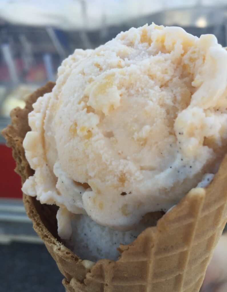 A vanilla ice cream with brown sugar in a waffle cone.