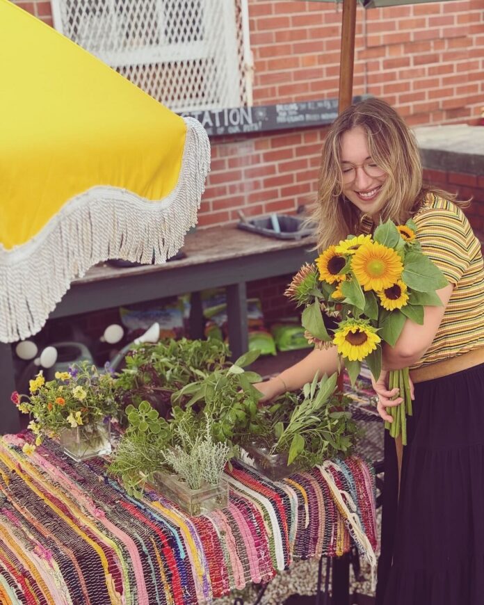 Spring Fling Market, a woman picks up yellow sunflowers from a table.