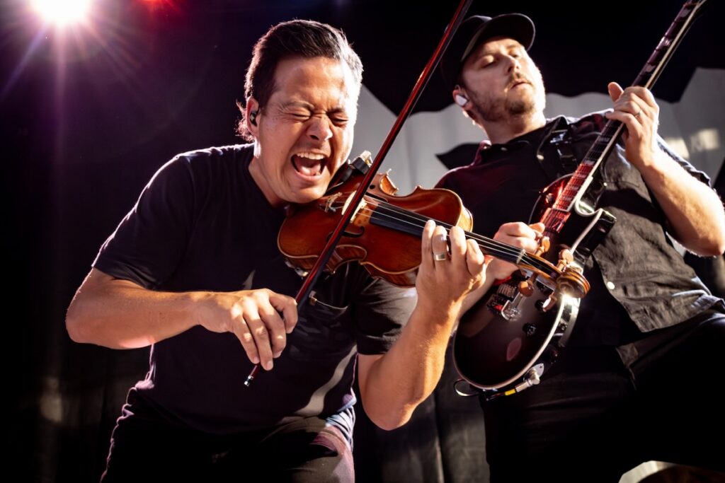 Violinist and guitarist for Yellowcard playing a concert on stage in Pittsburgh.