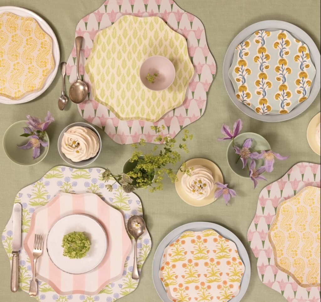 A variety of pink and yellow pattern plates on a green table.