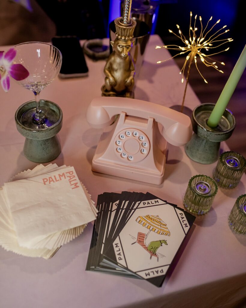A pink table setting with a telephone, cards, and green accents.