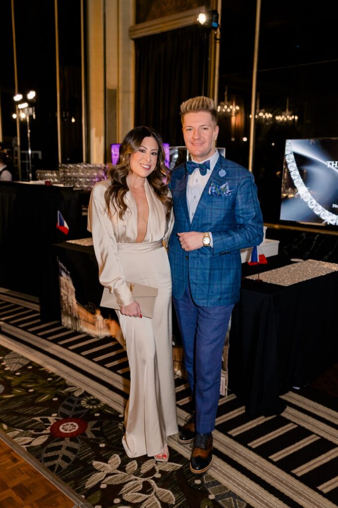 A man in an all blue suit and bowtie with a woman in a long white evening gown.