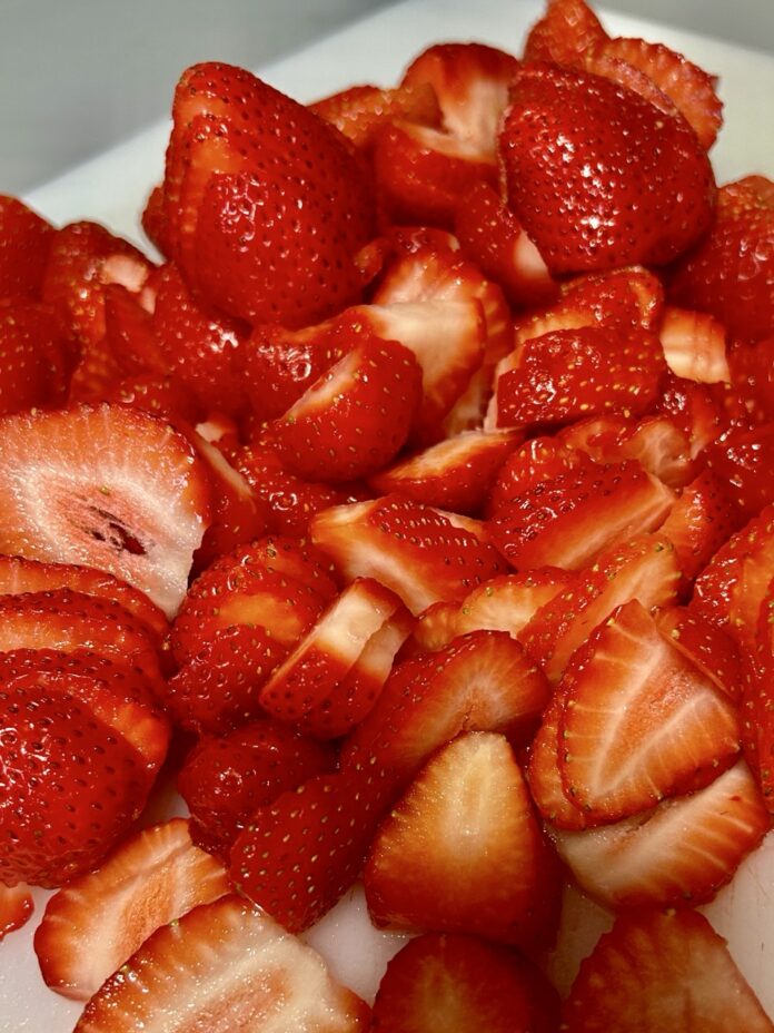 A cutting board full of sliced strawberries.