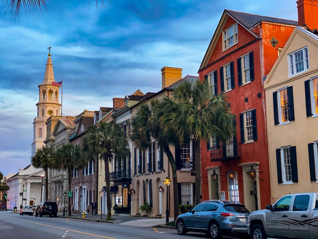 The outside of a line of houses sitting beside a church in Charleston.