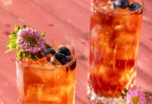 Earl Gray and Blueberry Punch Two tall glasses with Earl Gray and Blueberry Punch with blueberries on top and a flower garnish.