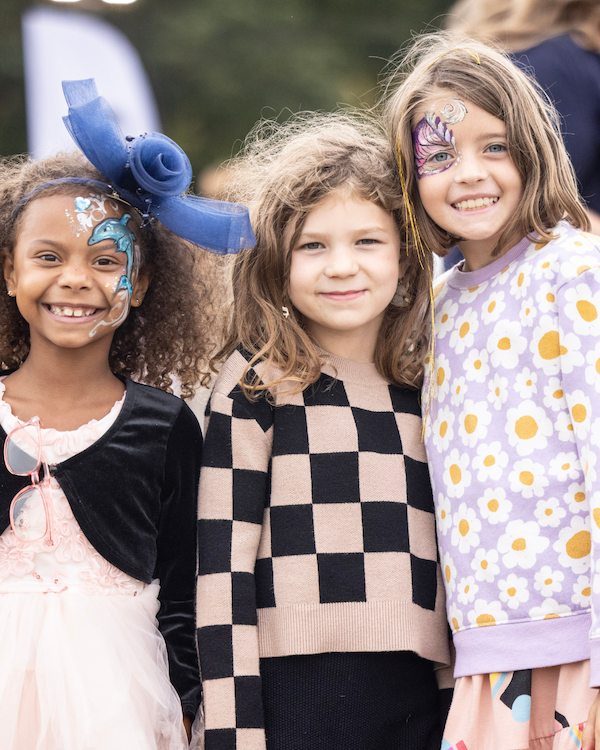 Three little girls, 2 with face paint, smiling at the camera.