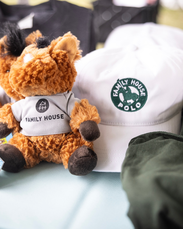 Merchandise, a little stuffed horse and a white ball cap with a logo, for the annual Family House Polo Match.