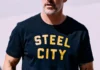 Find Gifts for Every Type of Dad This Father’s Day A man in a black shirt with yellow font that says "steel city" on it.
