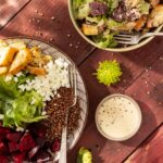 A grain bowl with quinoa, brown rice, greens, and beets sits next to a White Balsamic Dressing and another grain bowl.