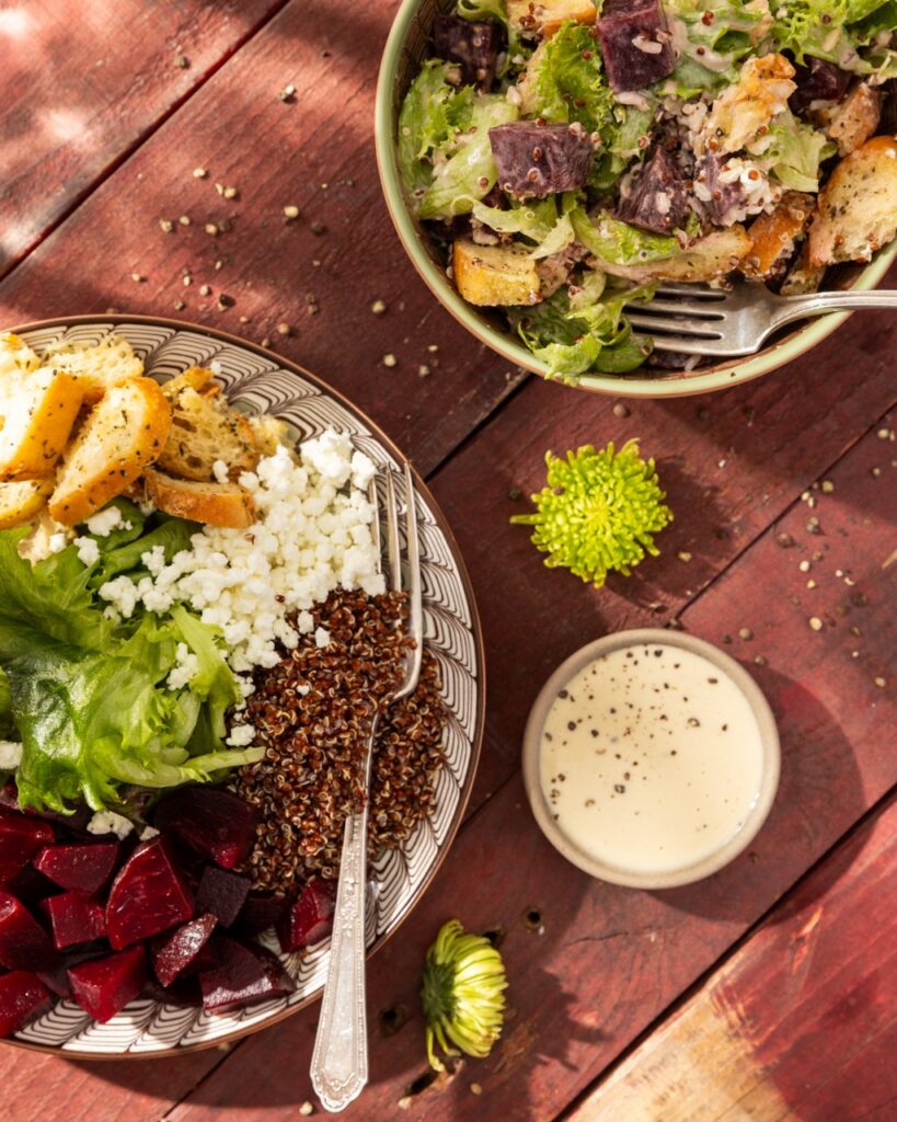 A grain bowl with quinoa, brown rice, greens, and beets sits next to a White Balsamic Dressing and another grain bowl.