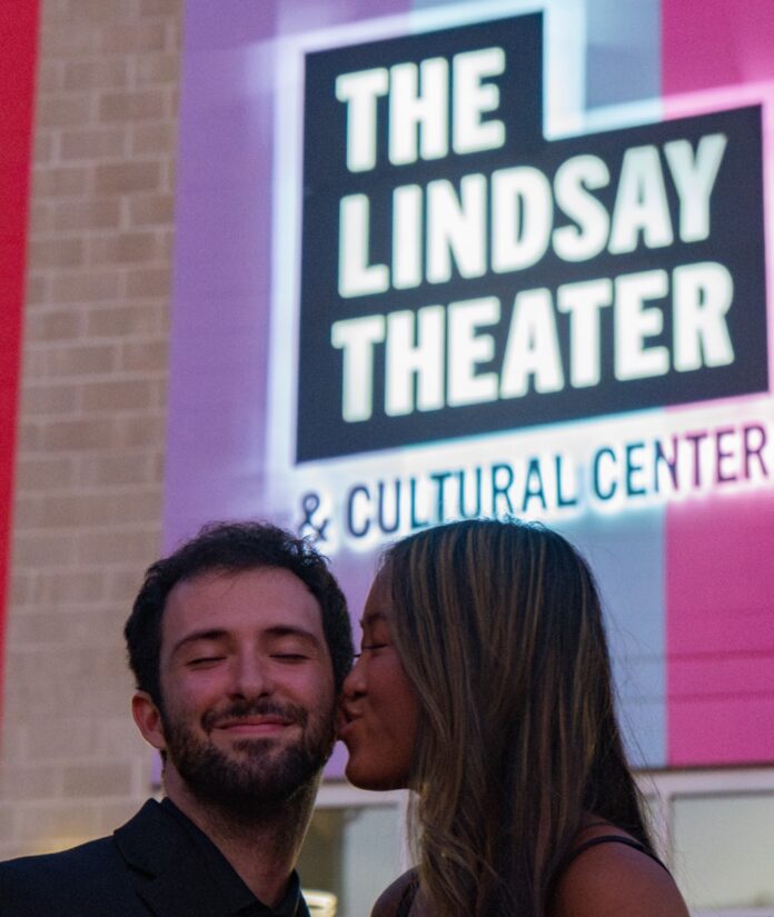 A woman kisses a man's cheek outside of The Lindsay Theater in Pittsburgh.