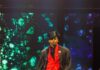 It’s About Time: Pittsburgh Opera Fashion Show 2026 A man walking down a runway in a red suit with a black top hat and black jacket over top.