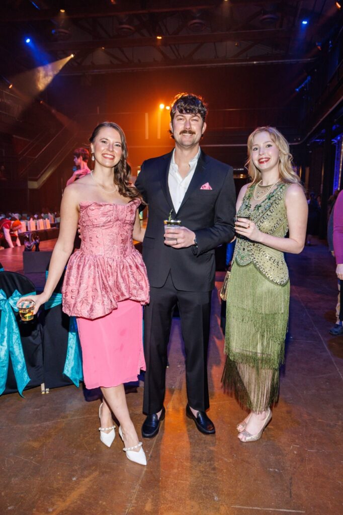 Two women in a pink and green dress with a man in a suit and pink pocket square.
