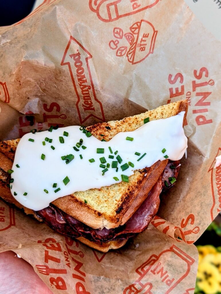 A triangle sandwich with ham and a bechemel sauce with parsley garnish.