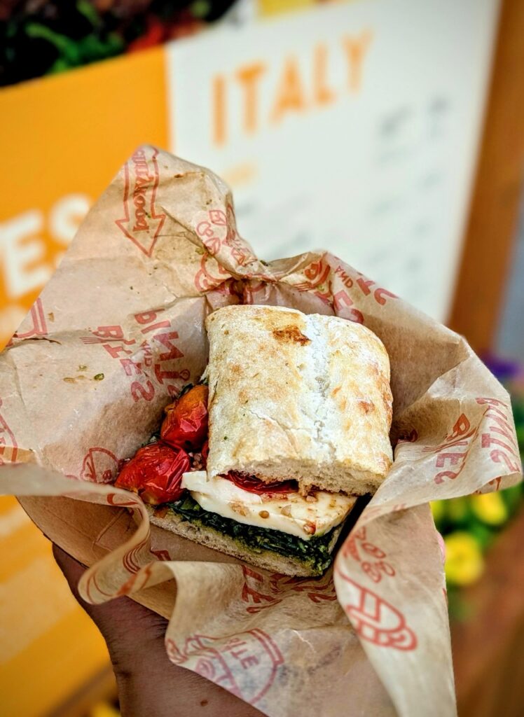 A ciabatta sandwich with basil, tomatoes, and burrata.