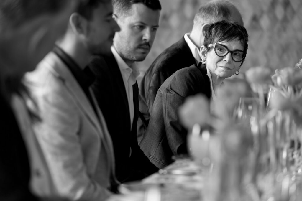 A woman peeks out from her place at the table, leaning forward.