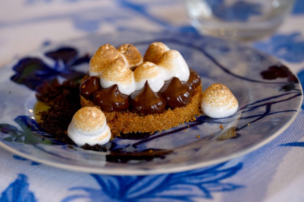 A s'mores tart with chocolate and Marshmallow on a blue and white plate.