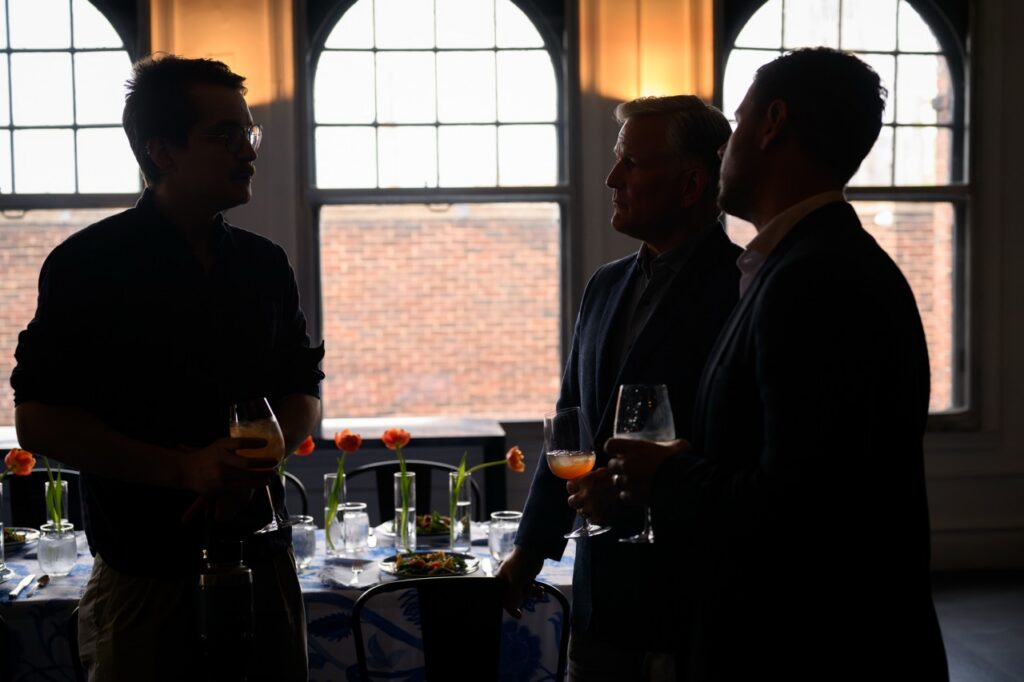 The shadow outlines of three men talking in front of a table.
