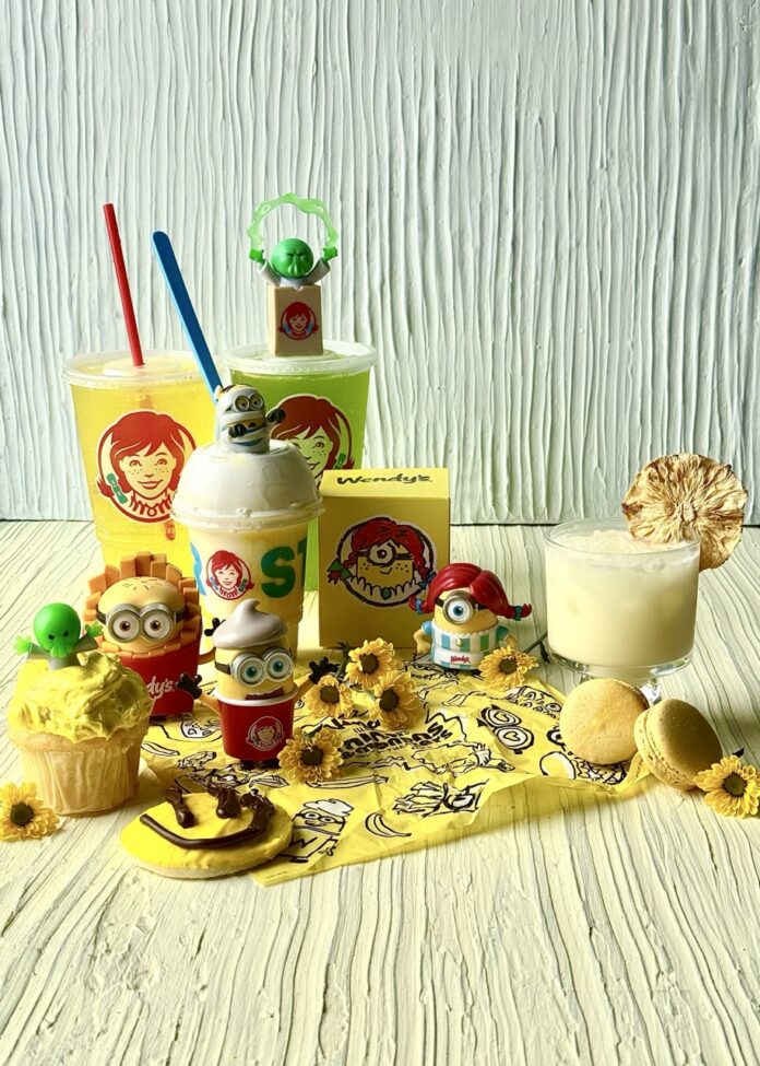 Create a 'Minions & Monsters' Feast Thanks to These Pittsburgh Establishments Frostys, drinks, Minion figures, small yellow flowers, a yellow cupcake, a yellow smiley cookie, and a creamy yellow cocktail sit on a table.