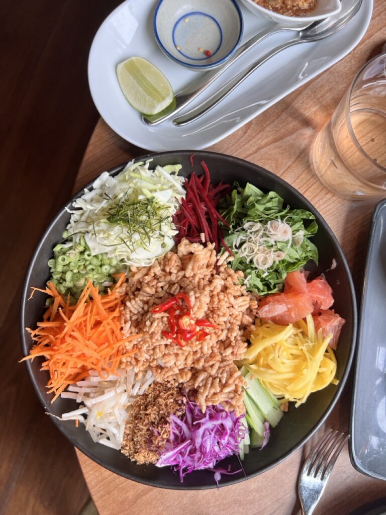 A black bowl full of vegetables in thin slices and grains.