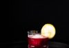 Construction Blue: A Spicy Blueberry Cocktail A short cocktail glass with a spicy blueberry drink inside and a lemon wheel as a garnish.