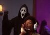 Collier’s Cuts: The ‘Scary Movie’ Spoof Series Returns in 2026 — Check Your Brain at the Door A man playing a game and hollering while the ghost face killer stands behind him with a knife.