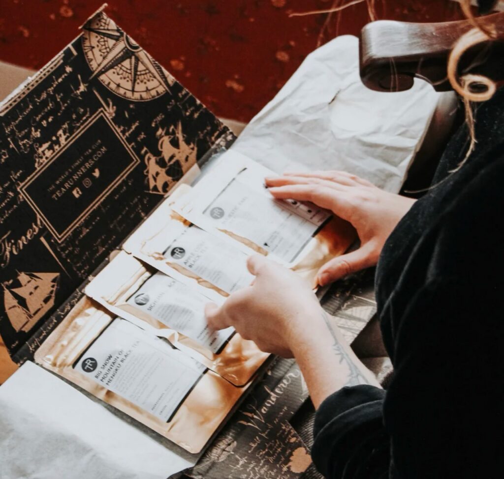 A person lays out bags of tea in front of a box.