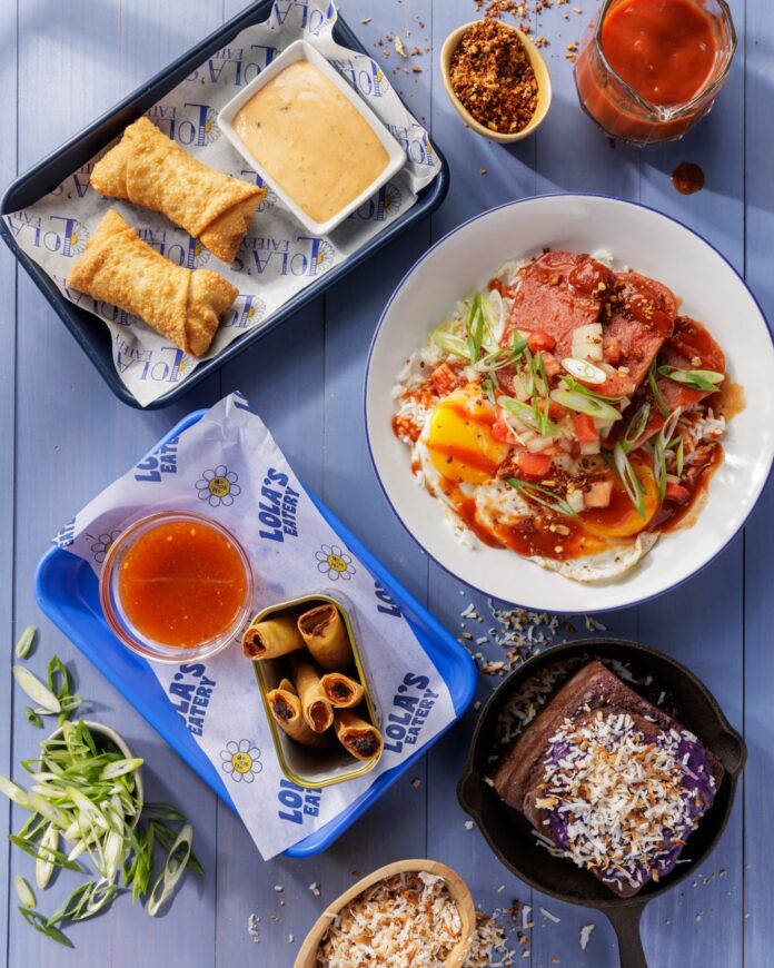 A variety of filipino breakfast dishes on a blue table in two rectangular plates, a round white plate, and a small skillet.
