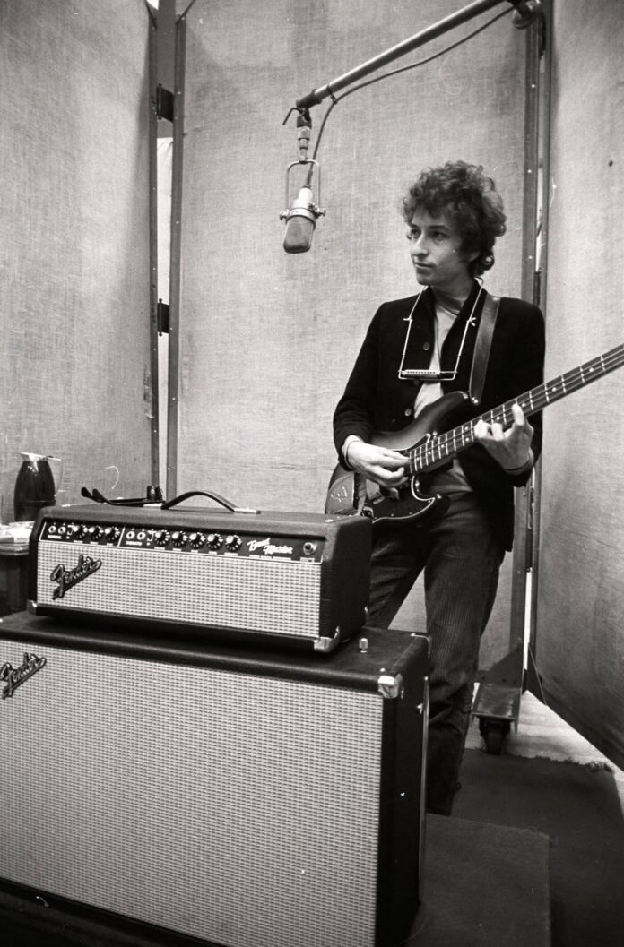 Bob Dylan playing his guitar in the recording studio back in the day.