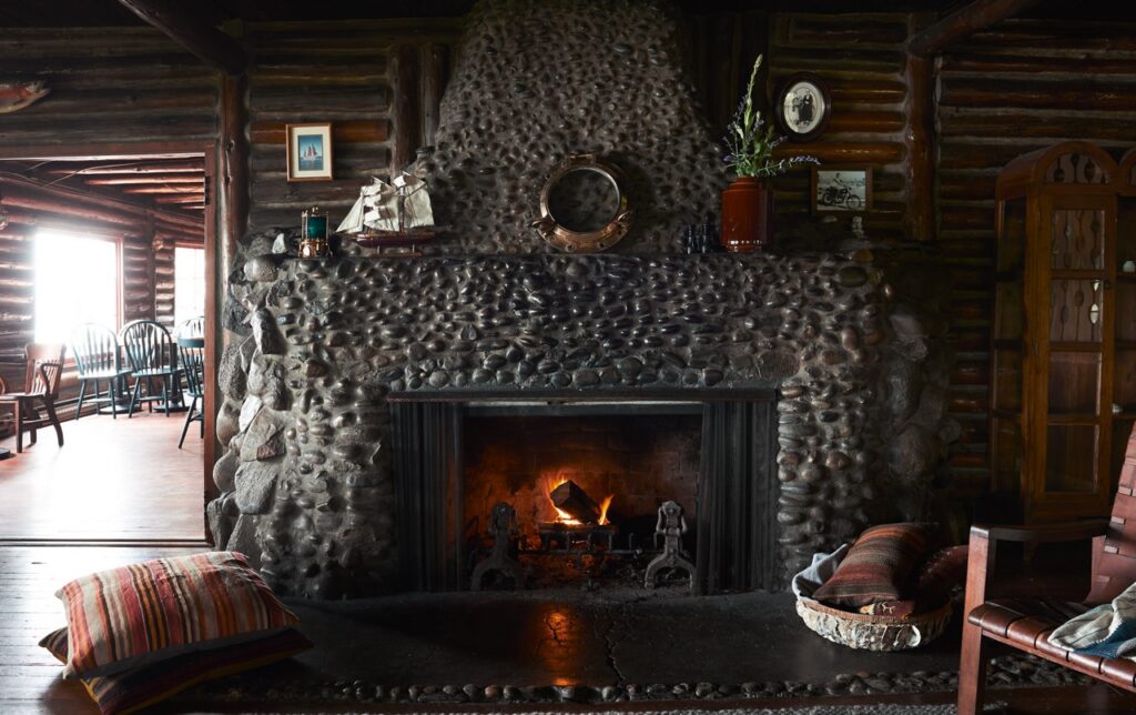 A stone fireplace against a dark wood wall.