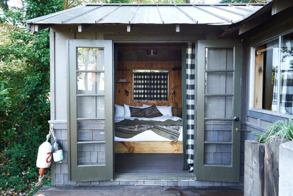A cabin with two grey doors open to a bedroom space.