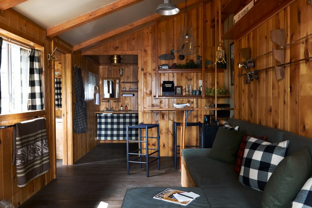 Wood walls of a cabin living area with shelves on them and a couch below it with checker pattern details.
