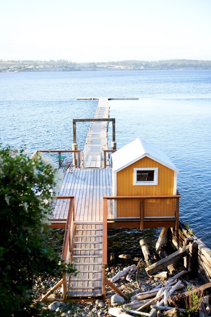 Escape to Whidbey Island TABLE Magazine 6 A dock leading out to a lake with a small yellow shack beside it.